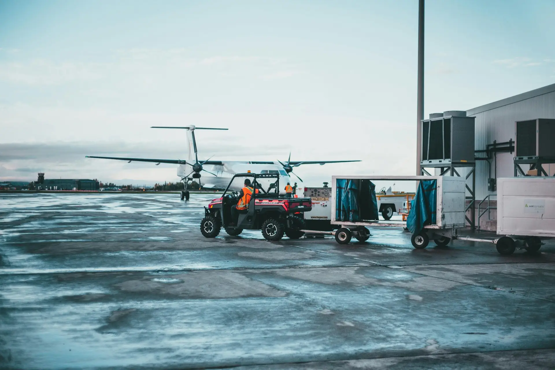 View of airport crew managing luggage near airplane at dawn.